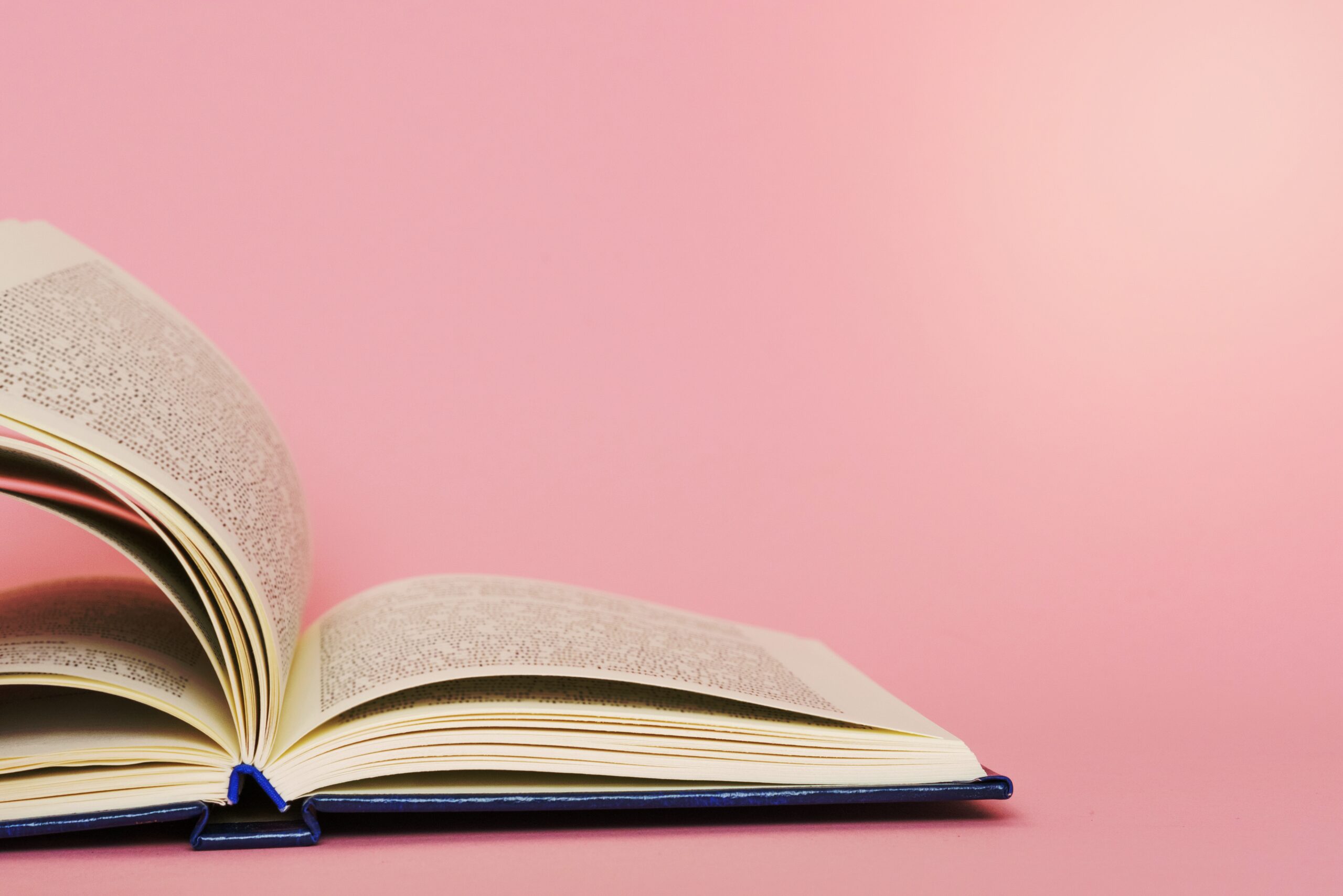 Open book page closeup on pink background, back to school education concept
