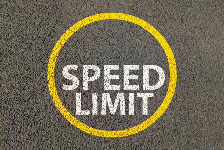 흰식 페인트로 SPEED LIMIT가 시멘트에 그려져있고 그 주위에는 노란색 원이 그려져있는 모습