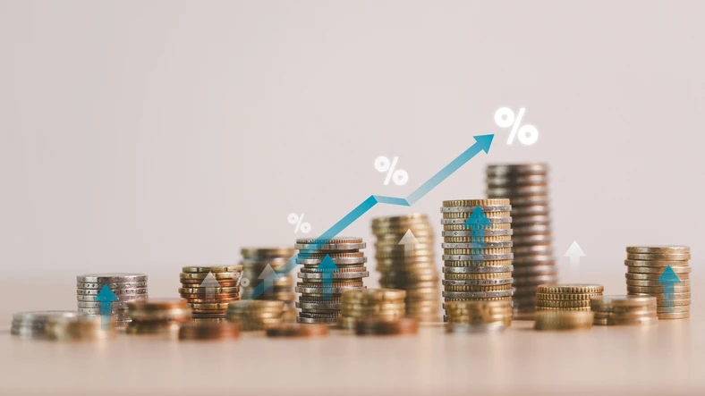 테이블 위에 동전이 있고 왼쪽에서 오른쪽으로 갈수록 많은 동전이 쌓여 우상향하는 그래프를 그리고 있는 모습